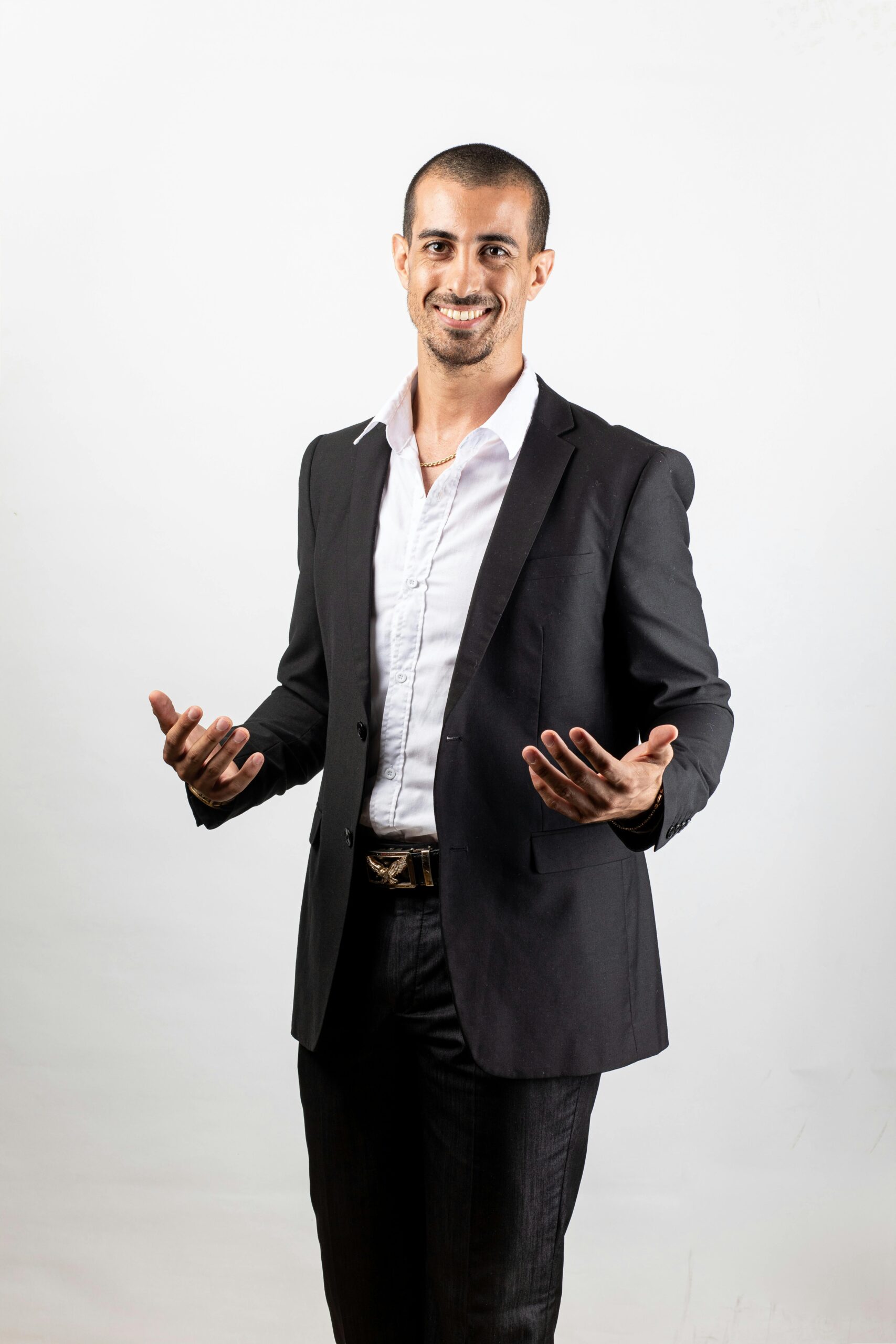 Confident businessman in formal attire smiling against a plain white background.