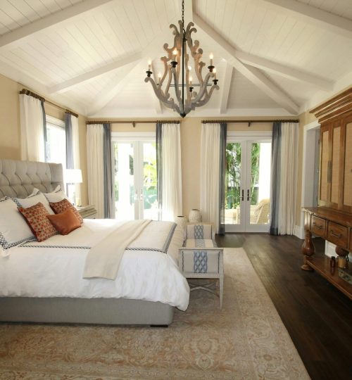 Stylish bedroom interior featuring a rustic chandelier, cozy bedding, and elegant wooden furniture.