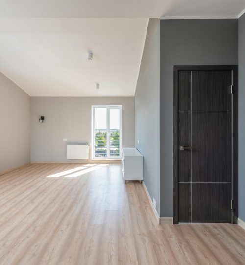 Spacious empty room with wooden flooring and large windows for ample natural light.